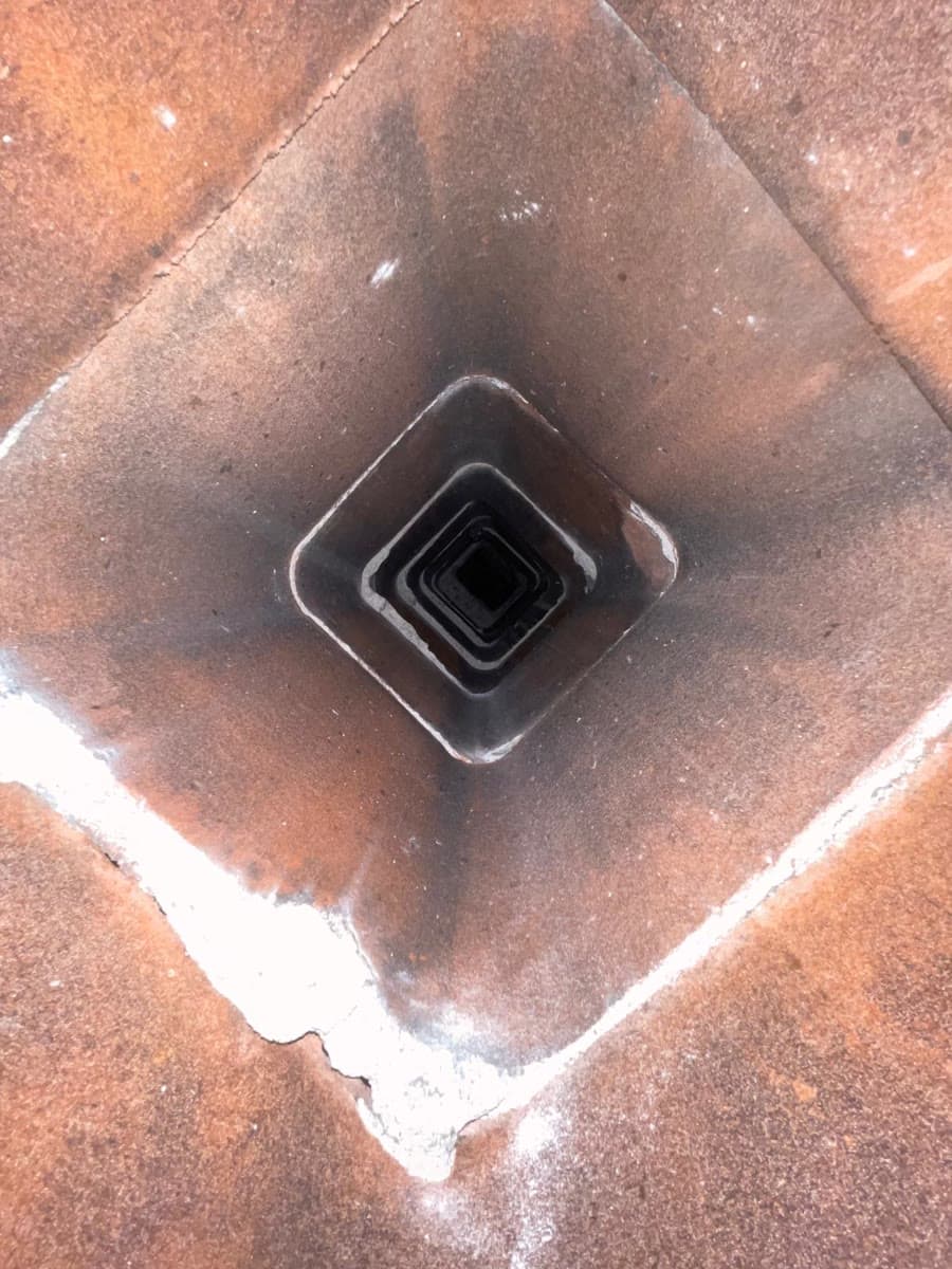 Looking down a square orange clay tile flue liner after sweeping, the tile clean and bare